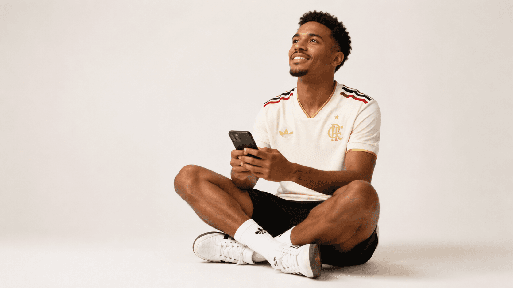 Torcedor sorrindo, sentado, segurando um celular