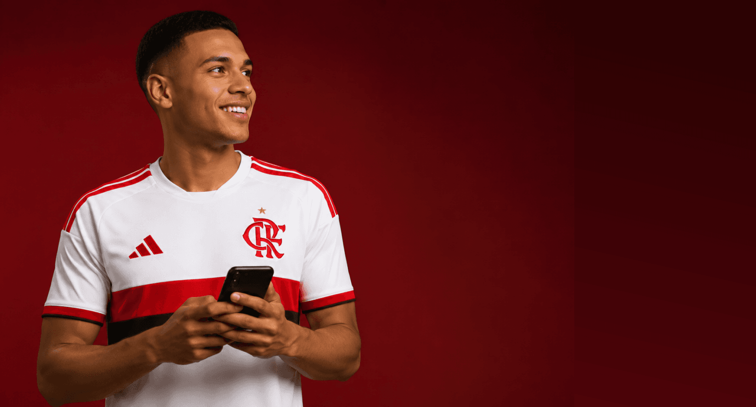 Jogador do Flamengo sorrindo, segurando um celular