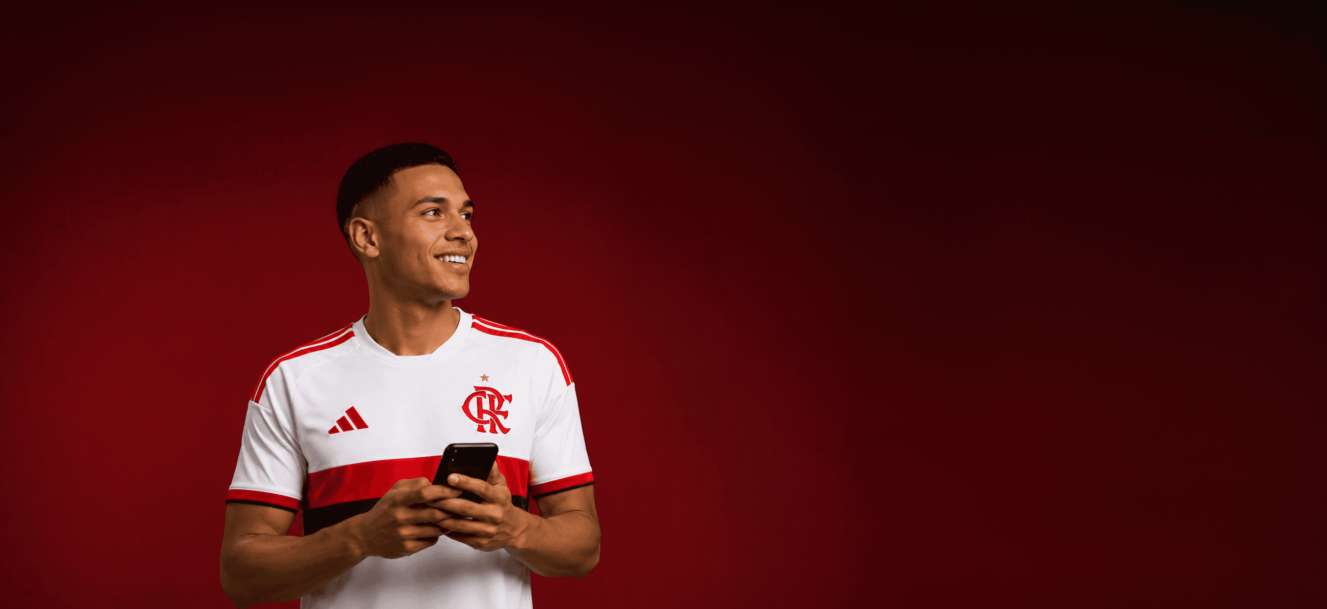 Jogador do Flamengo sorrindo, segurando um celular
